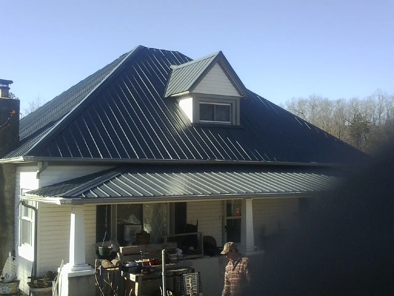 Dark blue standing seam metal roof with a dormer above a front porch in Hartford
