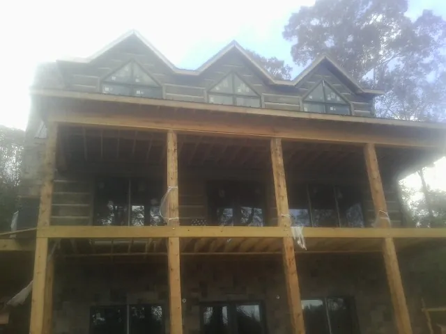 Dormers and porch framing on a large log home under construction — Roof Coating work by our crew in Hartford