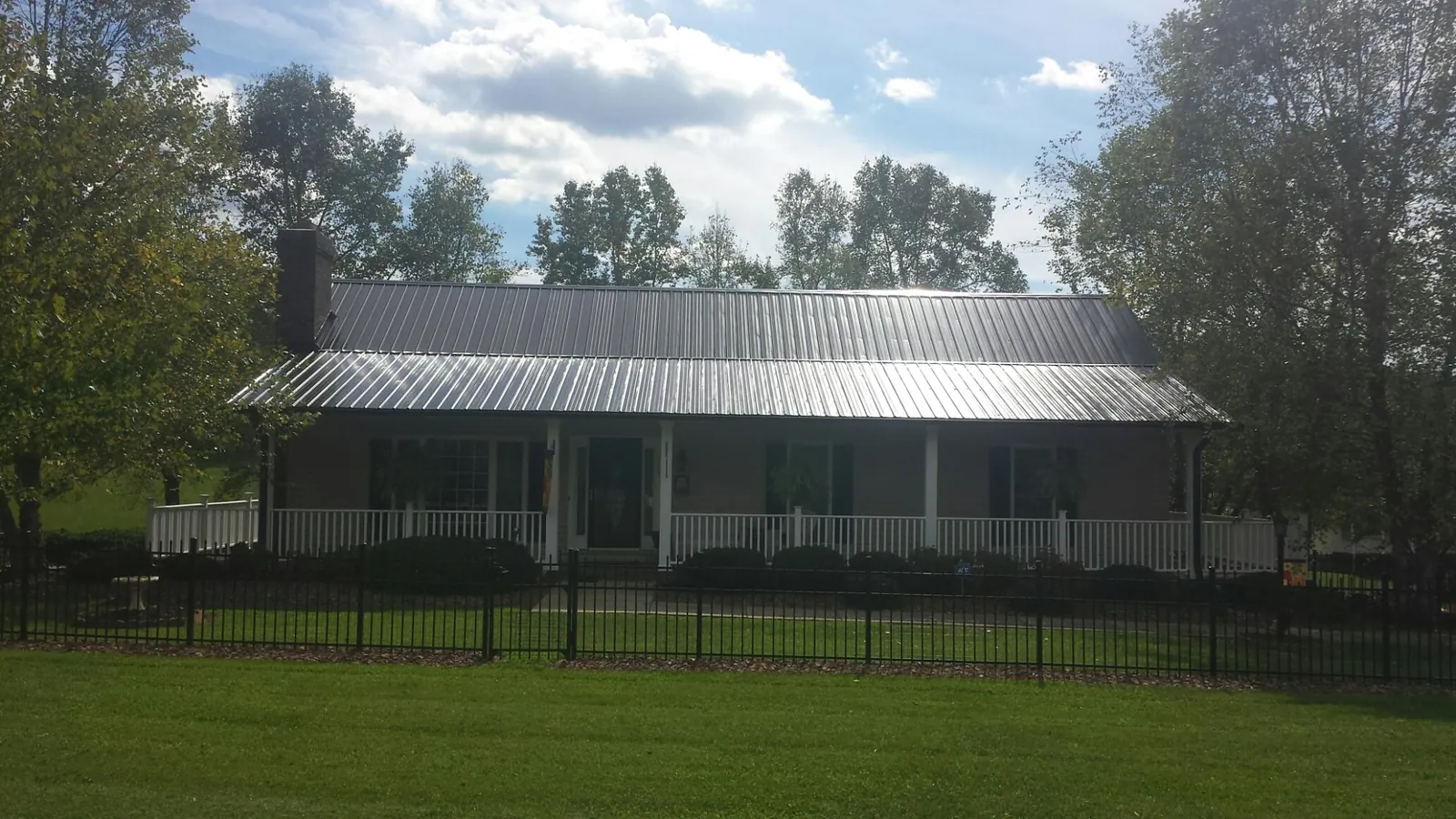 Gray metal roof on a brick ranch with a full width front porch — Gutter Guard Installation work by our crew in Hartford